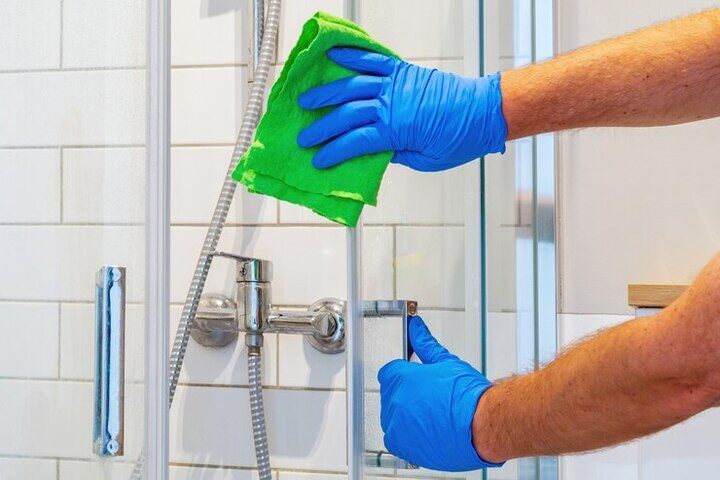 cleaner-washes-shower-door-bathr